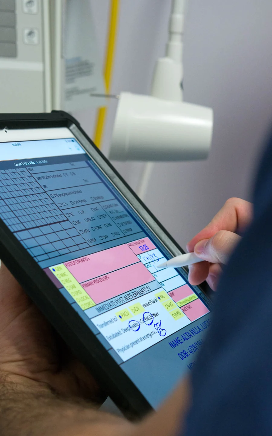 Apple Pencil entering information on an AnesthesiaEMR record with familiar handwriting and colored fields.